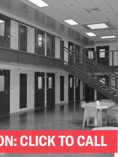 A black and white photo of a cell block with the words "Take Action; Click to Call"