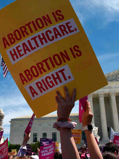 An ACLU sign reading Abortion is Healthcare. Abortion is a right. is waved in front of the U.S. Supreme Court