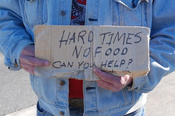 A person holds a sign that says Hard Times, No Food, Can you help?