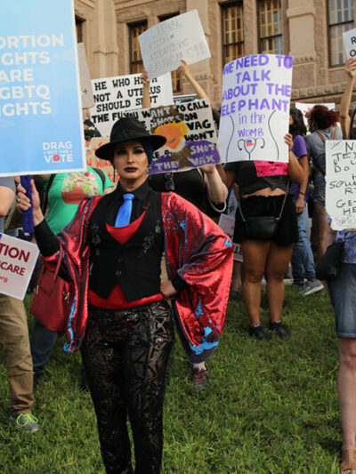 LGBTQ+ Protesters hold signs at an abortion rally