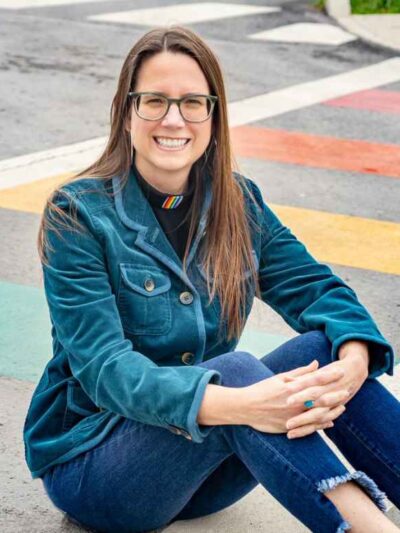Jenny Williams sits on a rainbow crosswalk