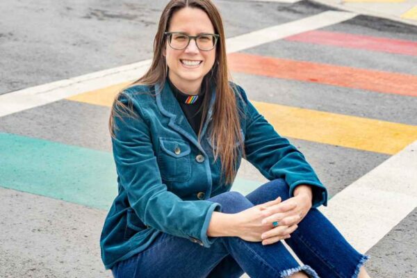 Jenny Williams sits on a rainbow crosswalk
