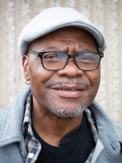 A portrait of Darrin Lester, a Black man with a light beard and dark-rimmed glasses.