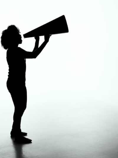 Silhouette of a person with a large megaphone against a grey background