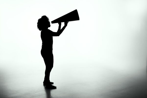 Silhouette of a person with a large megaphone against a grey background