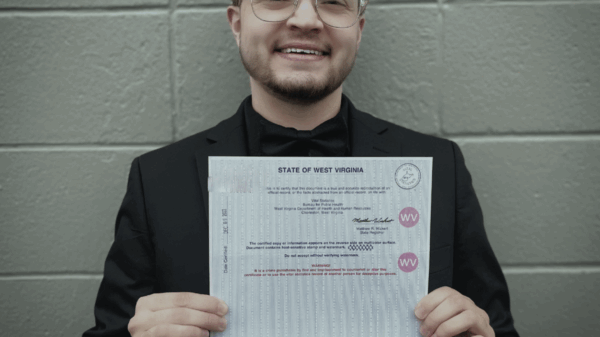 Xavier Hersom holds up a government document showing his corrected gender marker.