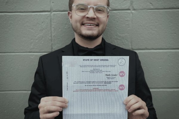 Xavier Hersom holds up a government document showing his corrected gender marker.