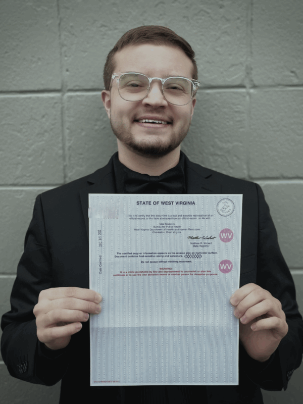 Xavier Hersom holds up a government document showing his corrected gender marker.