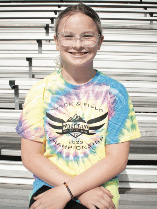 Becky Pepper Jackson sits on bleachers at her school wearing a tie-dyed shirt and glasses.