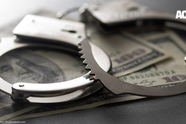 Handcuffs are shown with 100 dollar bills to symbolize the cash bail system