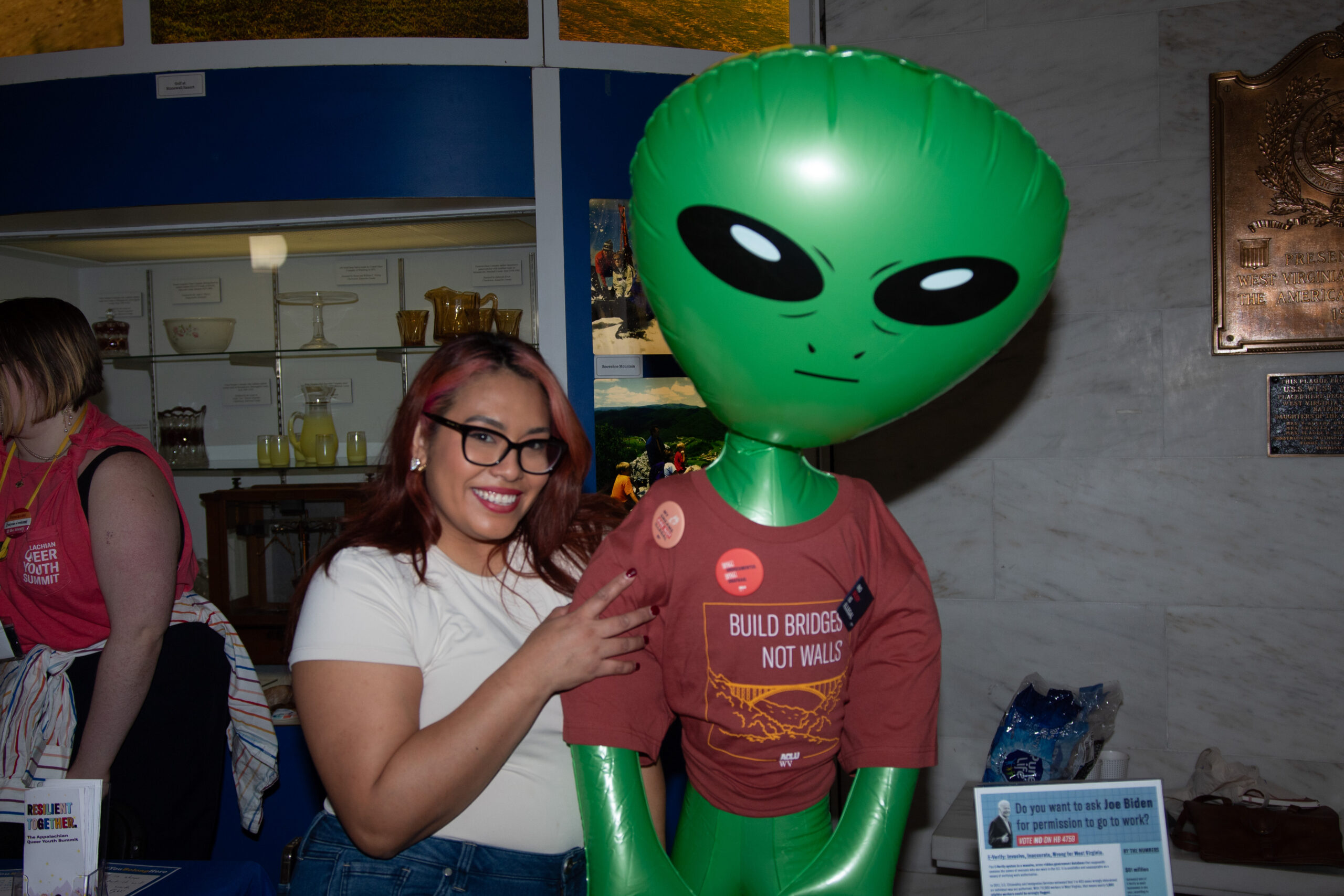 Immigrants' Rights Campaign Coordinator Jacki Lozano embraces an inflatable alien wearing an ACLU-WV tee shirt that says