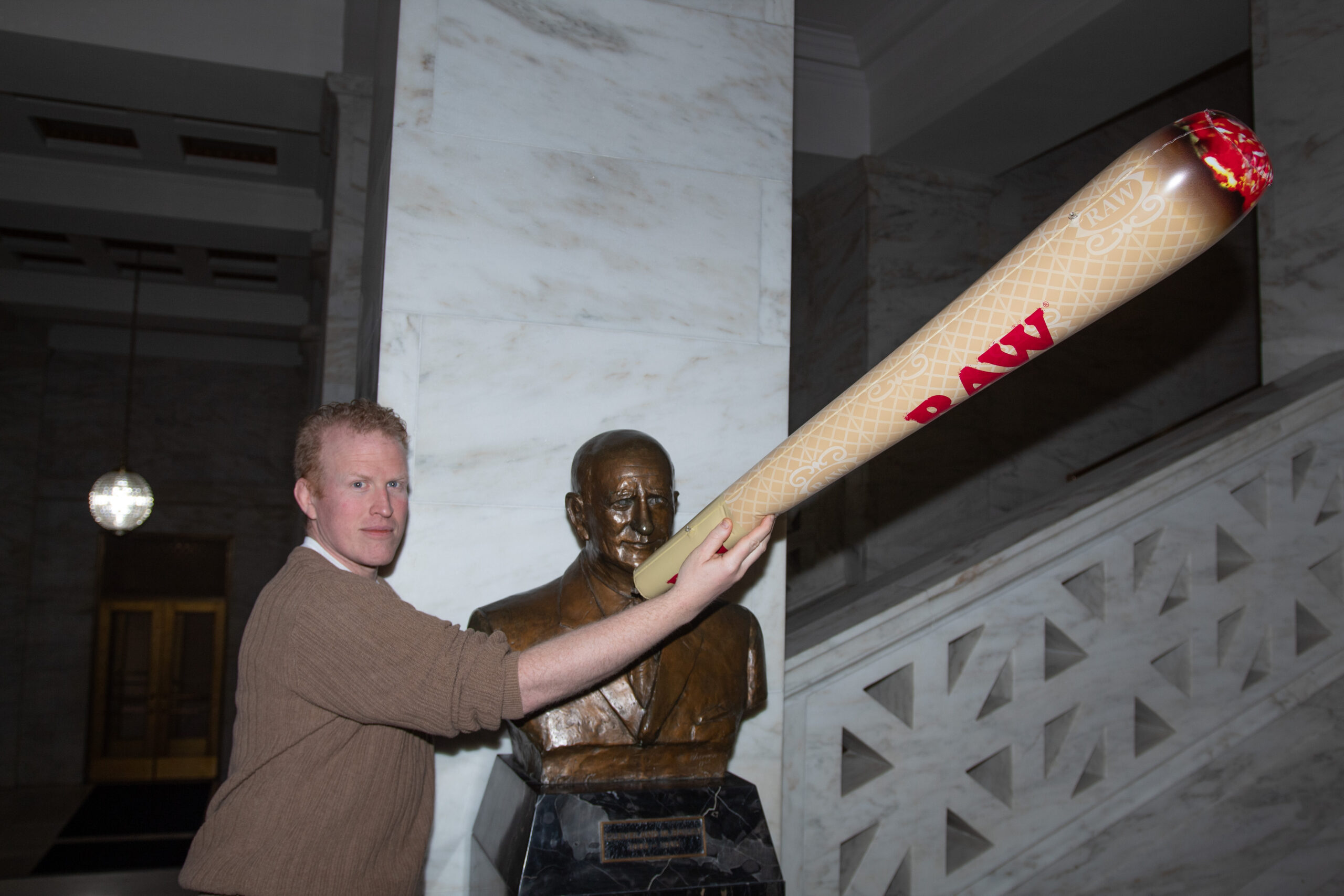ACLU-WV staffer Kyle Vass holds an inflatable joint in support of cannabis decriminalization in front of a Capitol statue.