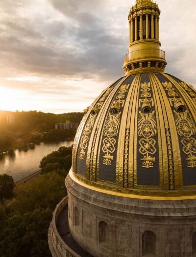 AN aerial shot of the WV Capitol's gold dome while the sun sets over the Kanawha River