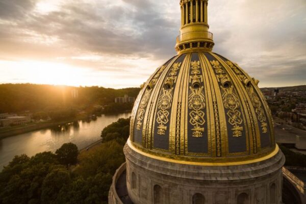 AN aerial shot of the WV Capitol's gold dome while the sun sets over the Kanawha River