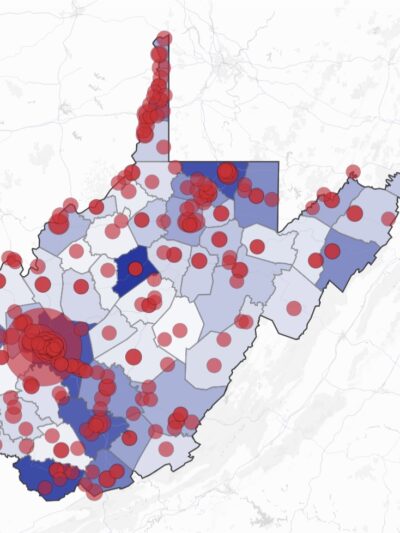 A data visualization map of West Virginia showing county boundaries with varying shades of blue (light to dark) overlaid with numerous red circles of different sizes distributed across the state. The circles appear most concentrated in the northern panhandle, southwestern region, and along the eastern border. The map uses a light gray base with subtle road networks visible in the background.