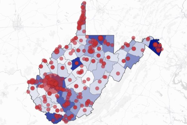 A data visualization map of West Virginia showing county boundaries with varying shades of blue (light to dark) overlaid with numerous red circles of different sizes distributed across the state. The circles appear most concentrated in the northern panhandle, southwestern region, and along the eastern border. The map uses a light gray base with subtle road networks visible in the background.