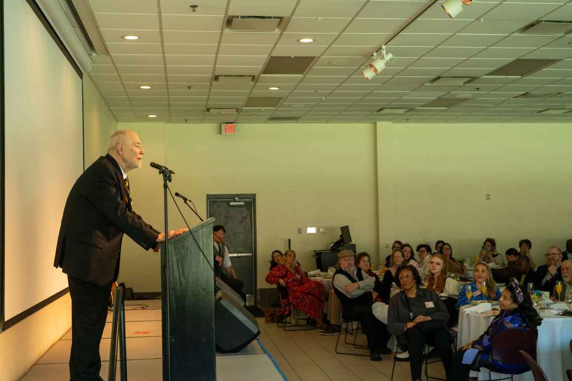 A man in a black suit address the audience after winning an award.