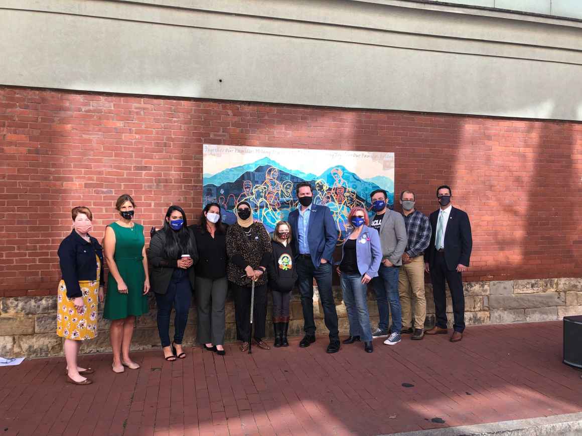 Partners pose for a picture in front of the mural