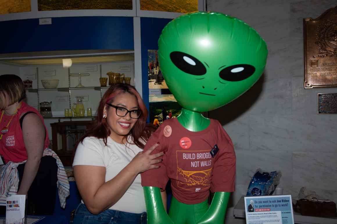 Immigrants' Rights Campaign Coordinator Jacki Lozano embraces an inflatable alien wearing an ACLU-WV tee shirt that says "Build Bridges Not Walls"