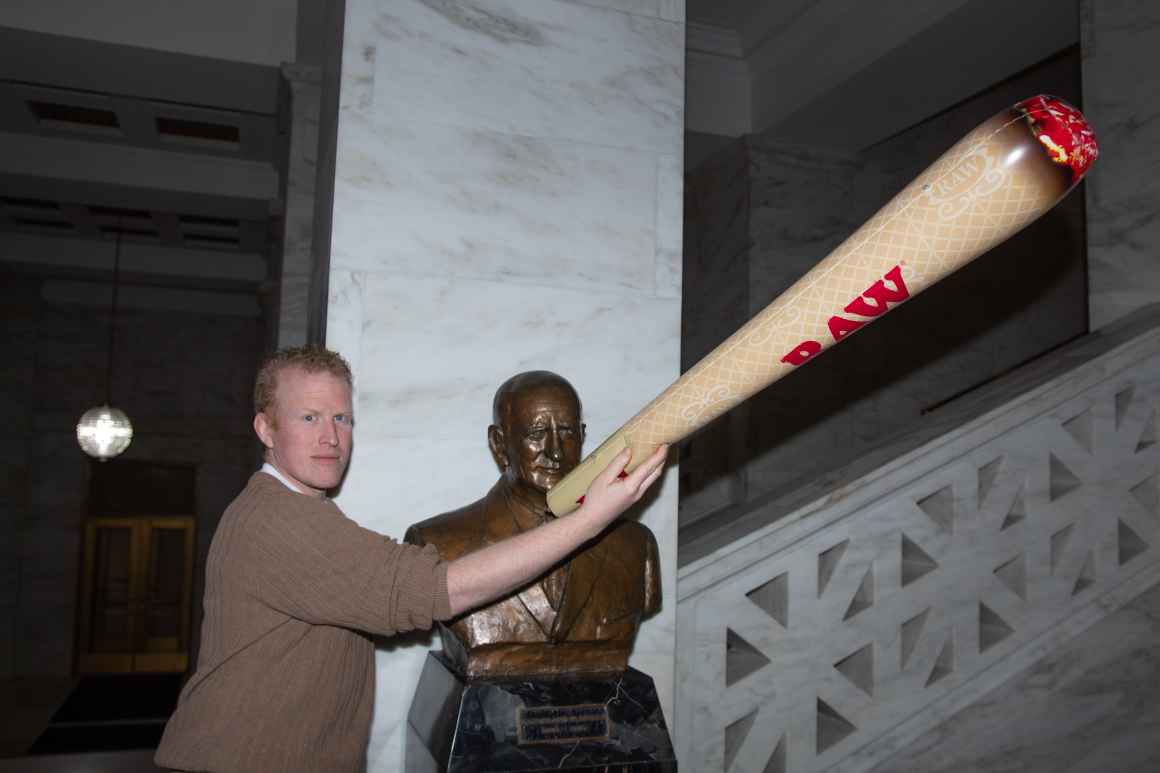 ACLU-WV staffer Kyle Vass holds an inflatable joint in support of cannabis decriminalization in front of a Capitol statue. 