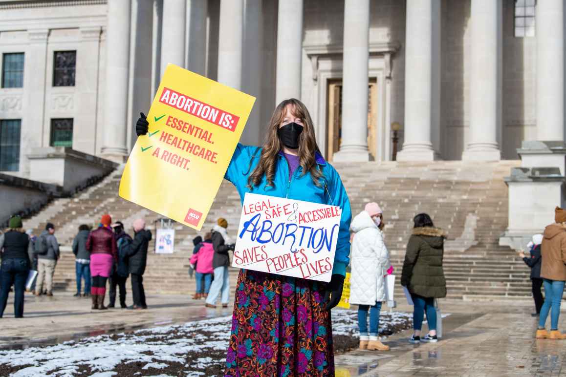 Protester holds an ACLU-WV sign at the state Capitol that says "Abortion is Essential, Healthcare, a Right"