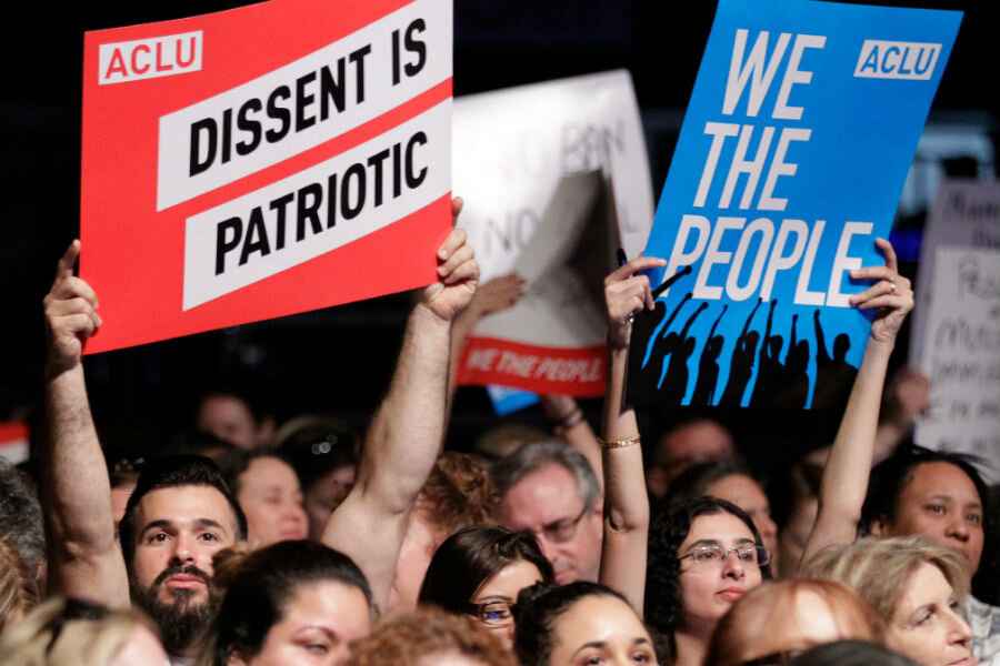 ACLU supporters hold signs that say "DISSENT IS PATRIOTIC" and "WE THE PEOPLE"