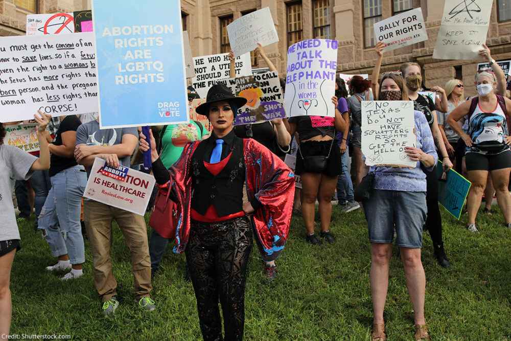 LGBTQ+ Protesters hold signs at an abortion rally
