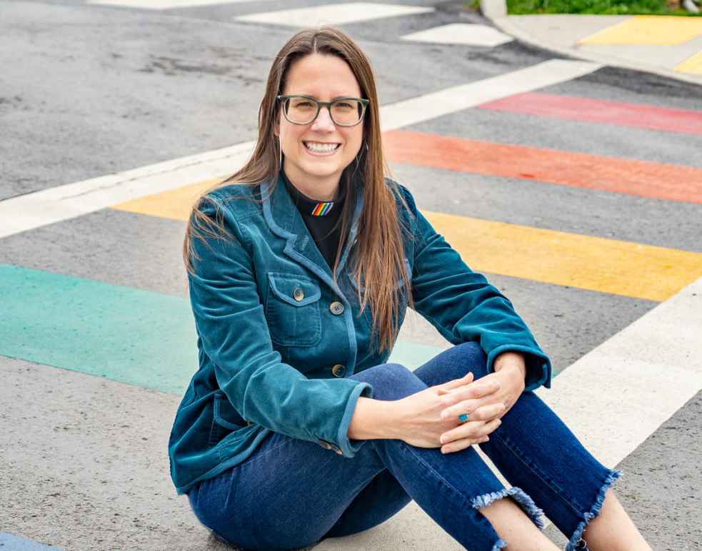 Jenny Williams sits on a rainbow crosswalk 