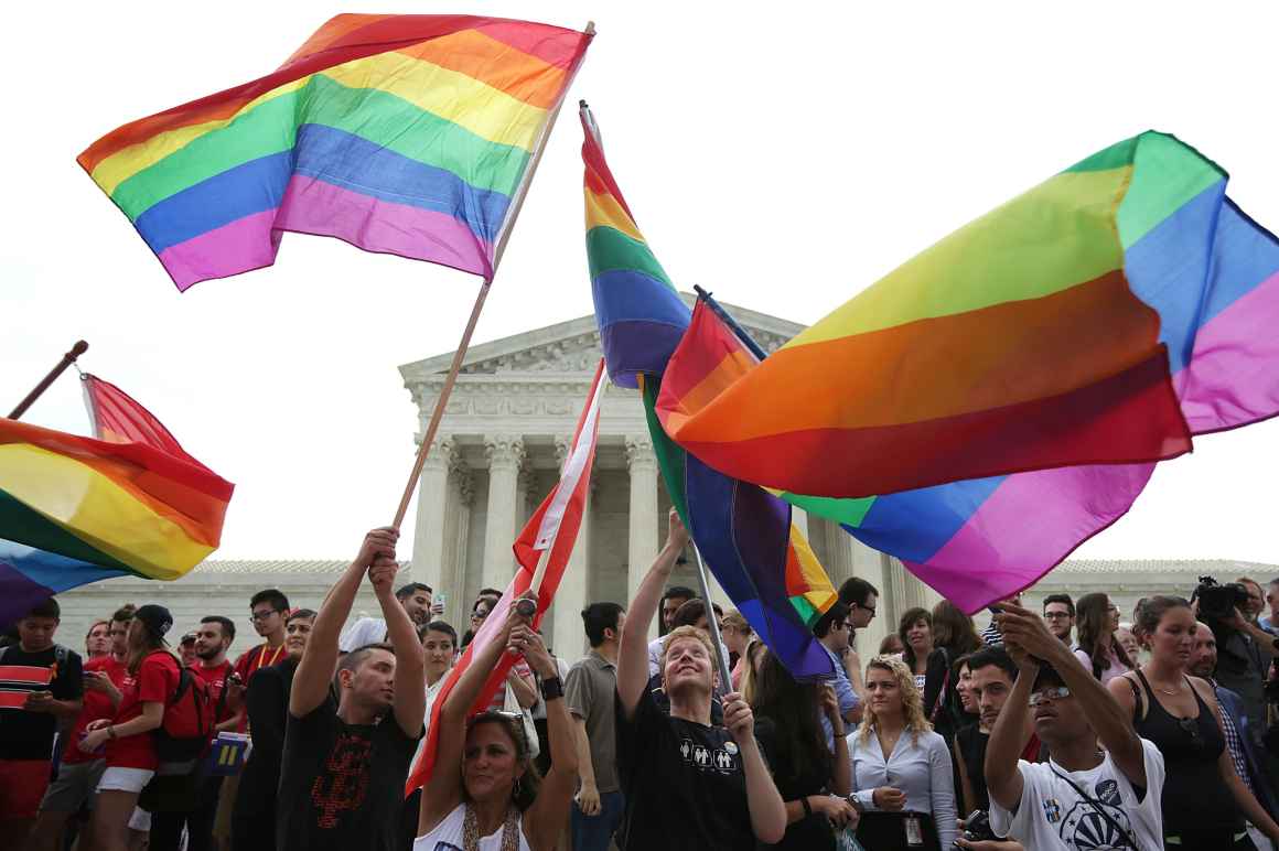 People wave rainbow flags in front of the U.S. Supreme Court building