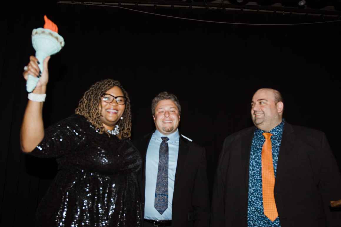 Danielle Walker holds a replica Lady Liberty torch high as Eli Baumwell and Joseph Cohen look on