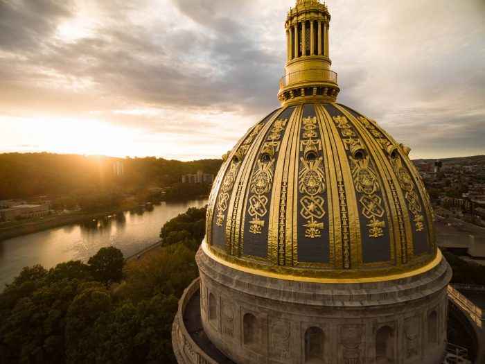 AN aerial shot of the WV Capitol's gold dome while the sun sets over the Kanawha River
