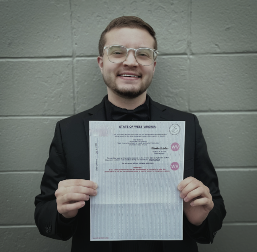 Xavier Hersom holds up a government document showing his corrected gender marker.