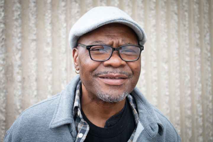 A portrait of Darrin Lester, a Black man with a light beard and dark-rimmed glasses. 