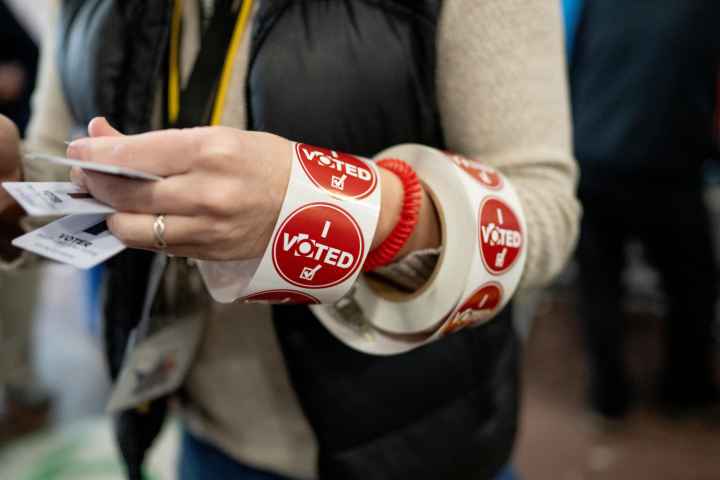 A ream of red "I voted" stickers wrapped around a poll workers arm. 