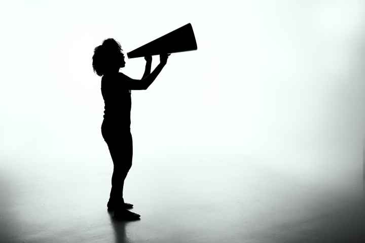 Silhouette of a person with a large megaphone against a grey background