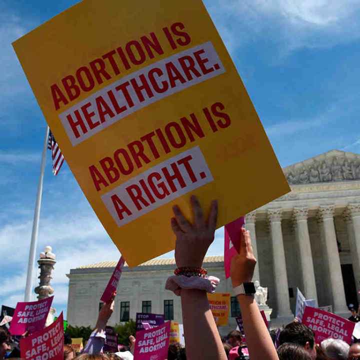 An ACLU sign reading Abortion is Healthcare. Abortion is a right. is waved in front of the U.S. Supreme Court