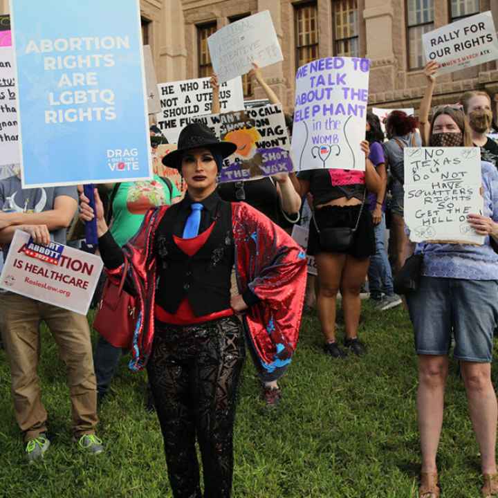 LGBTQ+ Protesters hold signs at an abortion rally