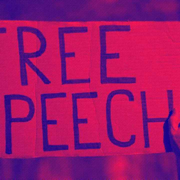 A protester holds a sign that says, "Free Speech."