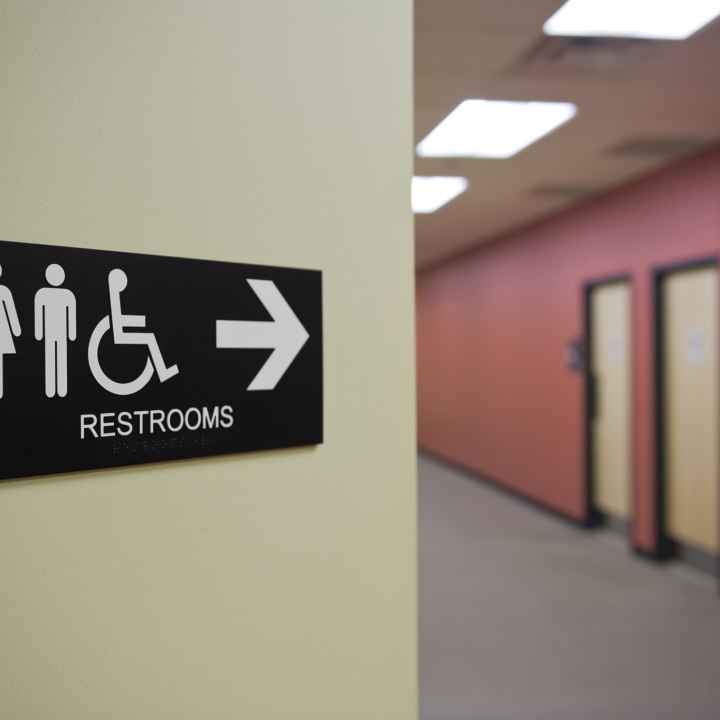 A sign points down a hallway to restrooms. 