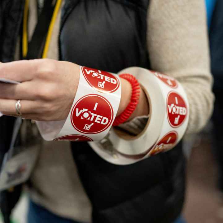 A ream of red "I voted" stickers wrapped around a poll workers arm. 