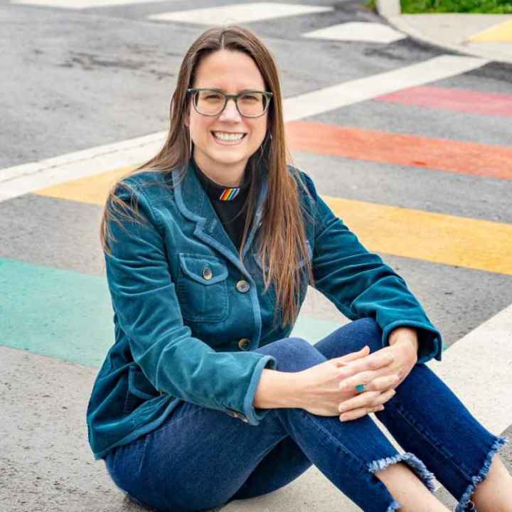 Jenny Williams sits on a rainbow crosswalk 