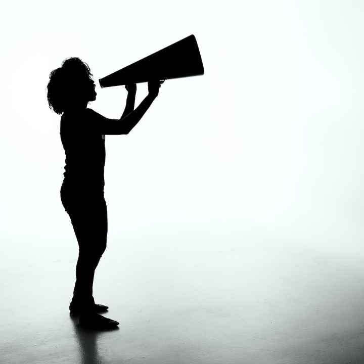Silhouette of a person with a large megaphone against a grey background
